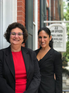 Portrait of Sharon and Anita in from of AMC Law office building.